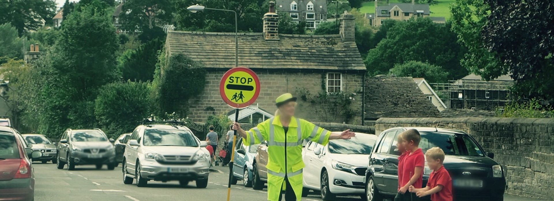 Lollipop officer in the road helping children to cross the road