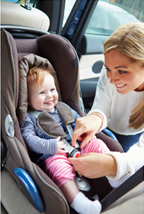 Woman strapping child into a rear facing car seat